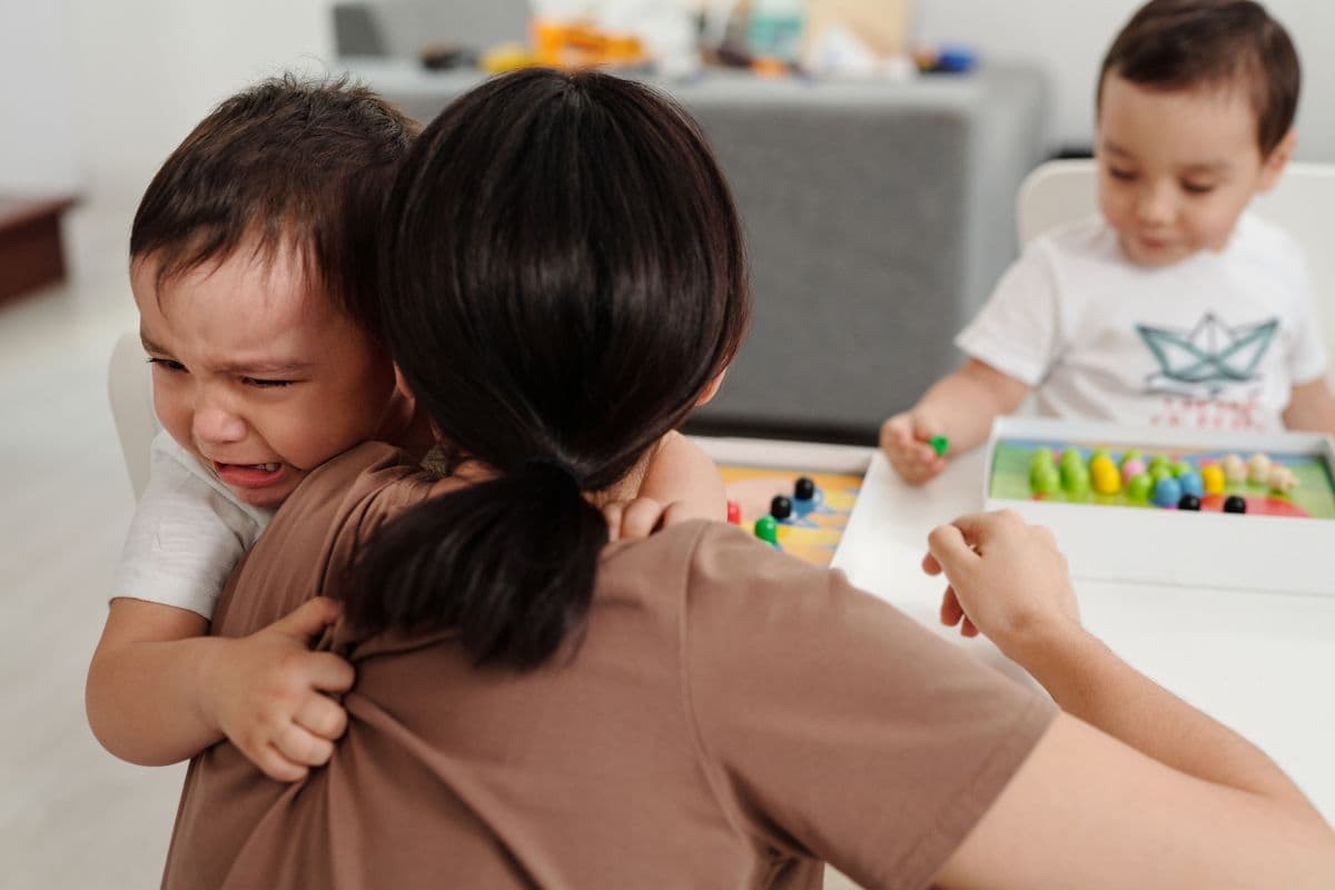 A mother comforts her crying child at home